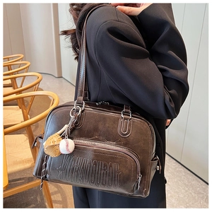 Detail of vintage brown tote bag with brand embossing and baseball charm accessory