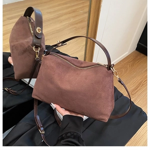 Detail of a brown matte faux suede pillow bag featuring wide top handles and gold hardware