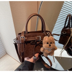 Close-up of leopard pattern handbag with silver buckle and plush dog charm accessory