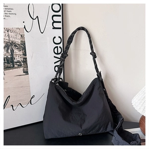 Detail of black nylon crossbody bag featuring stylish black and white woven rope handles
