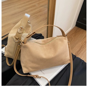 Detail of matte suede pillow bag featuring gold metal hardware and zipper closure
