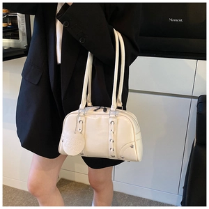 Detail of cream soft leather tote bag with silver metal eyelets and decorative woven straps