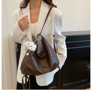 Detail of a dark brown leather hobo bag with a cloud charm and fashion label