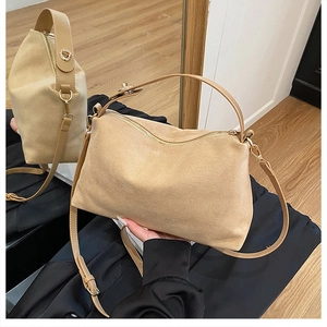 Detail showing beige suede crossbody bag with gold hardware and a soft slouchy shape