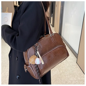 Macro shot of vintage brown leather tote bag with baseball themed charm details