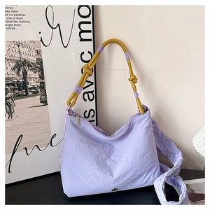 Detail of lavender pleated crossbody bag with yellow knotted rope strap and metal logo