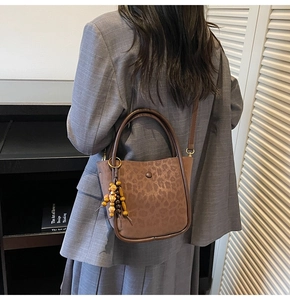 Detail of leopard print bucket bag with vintage wooden beaded tassel on model