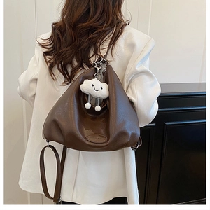 Detail of brown matte leather hobo bag with a cute white plush cloud keychain