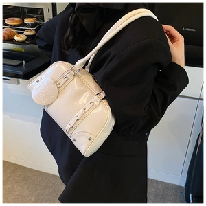 Detail of a white faux leather shoulder bag with silver studs and woven patterns