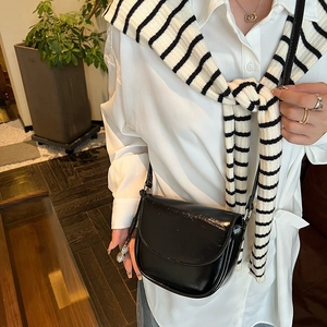 Detail of black glossy saddle bag featuring a unique peanut metal charm on the side
