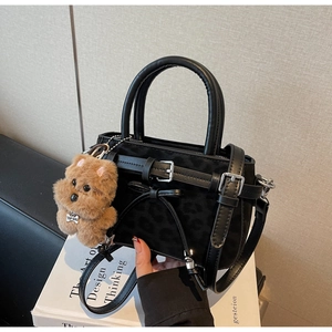 Detail of black leopard print handbag with bow decor, crossbody strap and teddy bear charm