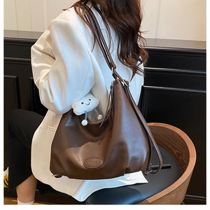 Close-up of brown vintage PU leather tote bag featuring a cute white cloud plush charm