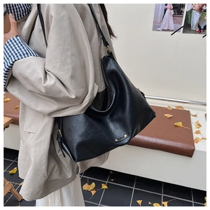 Detail der schwarzen Leder-Shopper-Tasche mit Fashion-Metalllogo und seitlicher Schnalle