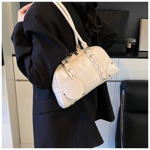 Detail of cream white leather tote with metallic studs and hanging embossed round charm