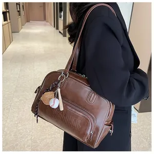 Detail of vintage brown tote bag featuring embossed letters and baseball charms