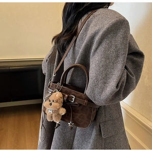 Close-up of leopard print crossbody bag with plush bear charm on grey wool coat