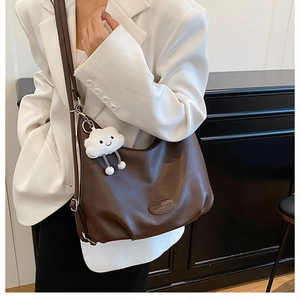 Detail of vintage brown large capacity tote bag with white cloud plush charm on a model