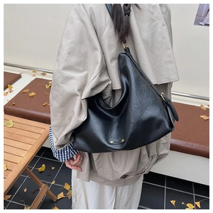 Detailaufnahme einer schwarzen PU-Leder-Hobo-Tasche mit Fashion-Metallplakette