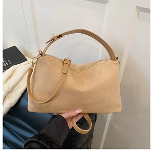 Detail of beige suede pillow bag featuring matte texture and adjustable shoulder strap
