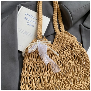 Detail der khakifarbenen geflochtenen Netztasche mit Perlenbogen und Spitzenbändern