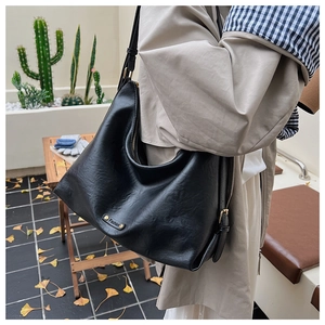 Nahaufnahme einer schwarzen Shopper-Tasche aus genarbtem Leder mit goldenem Namensschild