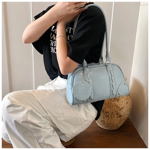 Detail of light blue soft leather tote bag featuring metal rivets and embossed logo tag