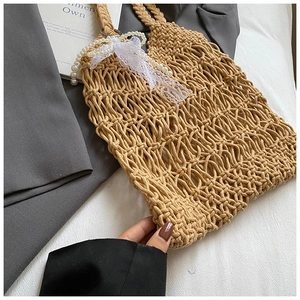 Close-up of khaki woven mesh tote with pearl handle and white lace bow detail