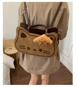 Detail of cat shaped backpack featuring soft brown suede fabric and cute face embroidery