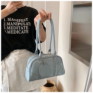 Detail showing the light blue leather tote bag with rivet studs and woven stitching