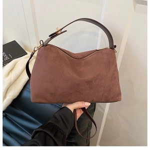 Detail of brown suede tote bag with golden zipper and leather handles for autumn style
