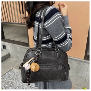 Detail of grey retro tote bag with baseball pendant and荔枝纹 texture shown on shoulder