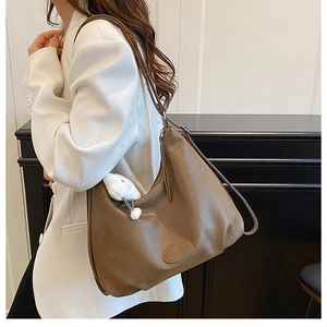 Brown vintage hobo bag with plush bunny charm worn by model in white suit
