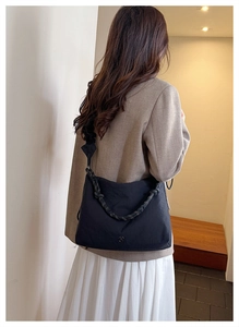 Detailed back view of a black canvas crossbody bag featuring a unique knotted wide strap
