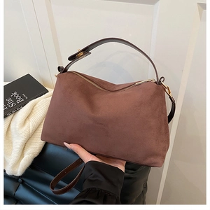 Detail of a brown suede hobo bag with a gold metal zipper and leather strap for women