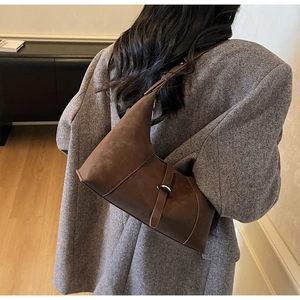 Detailed back view of vintage brown suede crescent underarm bag on a grey coat