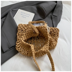Detail of hand-woven hollow mesh tote bag with braided handles on a minimalist background