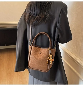 Brown leopard print bucket bag featuring wooden bead charms and retro matte finish texture
