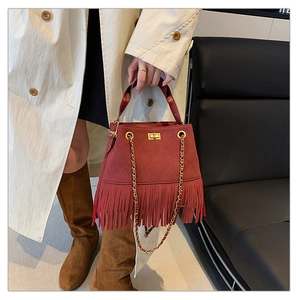Détail du sac seau bordeaux en daim avec franges longues et fermoir rotatif doré