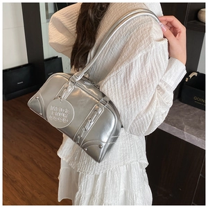 Detail view of silver metallic leather tote bag with rivet studs and embossed round tag