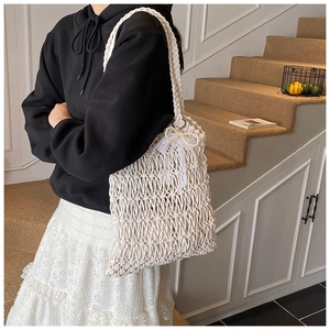 Close-up of cream woven tote bag with lace bow and pearl details on shoulder
