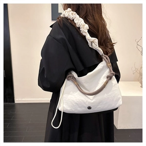 Detail of white nylon tote bag featuring ruffled shoulder strap and rope knot handle detail