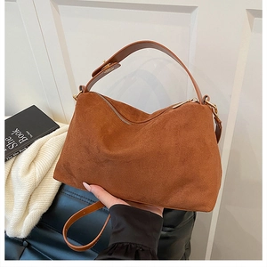 Detail of brown suede leather handbag showing soft matte texture and gold hardware details