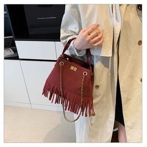 Détail du sac seau bordeaux matelassé avec des franges en cuir et chaîne dorée