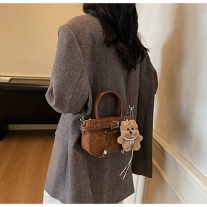 Detail of leopard print handbag with cute plush dog charm and bow strap accents
