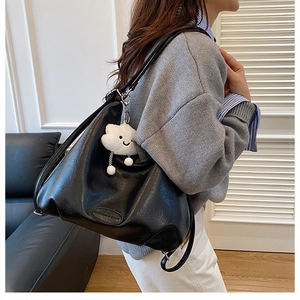 Close-up of black PU leather tote bag with cloud charm and embossed fashion logo
