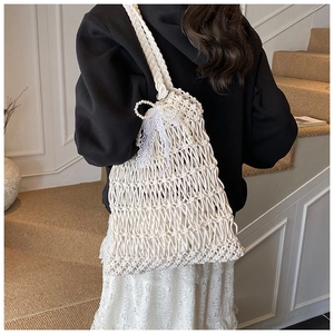 Detail of white handmade woven tote bag with pearl bow and lace ribbons on shoulder