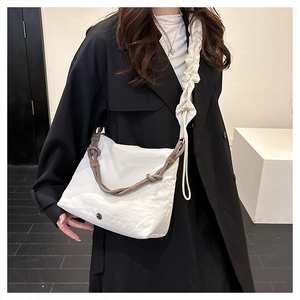Detail of white pleated dumpling bag with brown rope handle and silver metal logo accent