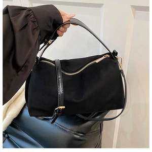 Detailed close-up of a matte black Boston bag featuring golden hardware and a long strap