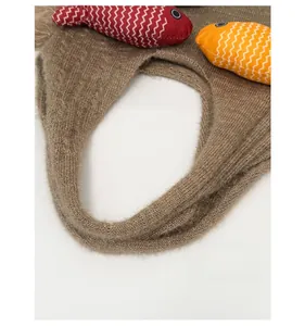 Close-up of soft brown knitted tote bag handle with colorful fish doll charms