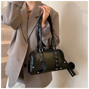 Close-up of black glossy leather tote bag showing metallic eyelets and leather tag detail